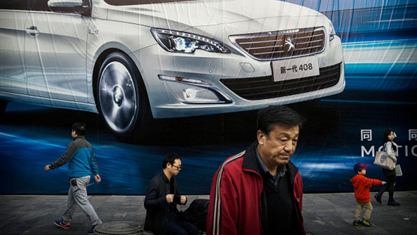 Chinese residents walk past an auto ad