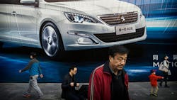Chinese residents walk past an auto ad Chinese residents walk past an auto ad