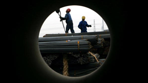 Workers unload steel at a products exchange market