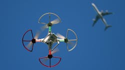 A small drone flies with a plane in the background A small drone flies with a plane in the background
