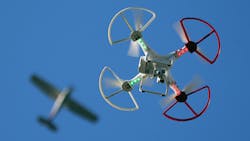 A quadcopter drone hovers far below a commercial airliner A quadcopter drone hovers far below a commercial airliner