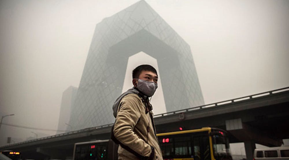 A Chinese man wears a mask as he waits to cross the road near the CCTV building during heavy smog on November 29 in Beijing. (Photo by Kevin Frayer/Getty Images)