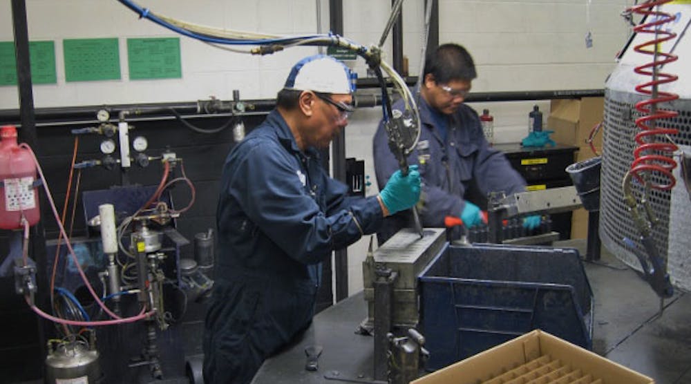 Operator Carlito Deala (foreground) molds the friction control solid sticks, while Operator Joemar Forteleza removes the sticks from a mold, in the recently redesigned solid stick production area.