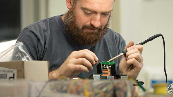 Tim Gillespie electronics community manager solders control boards in the FirstBuild lab where community members come together to build prototypes of next generation appliances