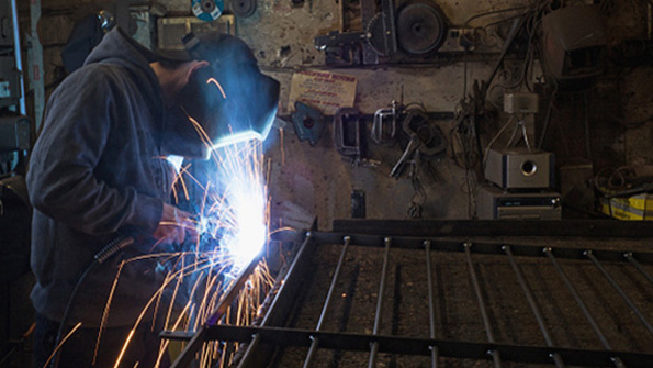 A worker welds a gate at a small fabricating shop