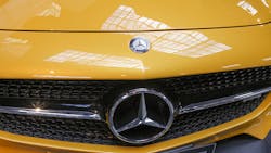 The Mercedez Benz logo on the hood and grille of a car The Mercedez Benz logo on the hood and grille of a car