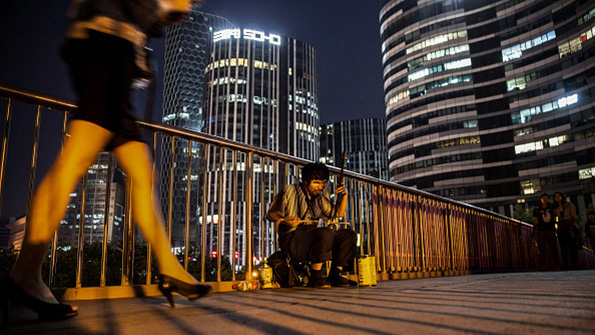 A Chinese busker plays in the shadow of skyscrapers