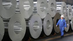 A worker walks past rolls of semifinished aluminum A worker walks past rolls of semifinished aluminum