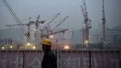 A Chinese laborer stands outside a worksite A Chinese laborer stands outside a worksite