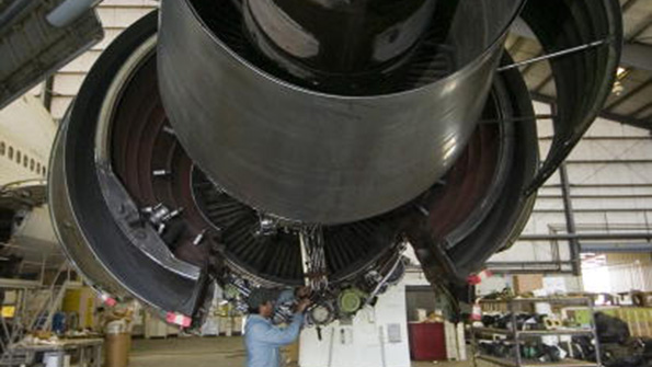 A factory employee works on an engine