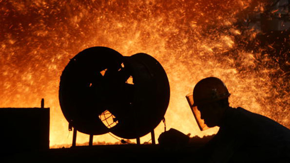 A Chinese steelworker labors in front of a blast furnace