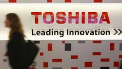 A woman walks past a Toshiba logo display A woman walks past a Toshiba logo display
