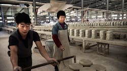 A pair of workers push a cart at a factory in Dehua China A pair of workers push a cart at a factory in Dehua China