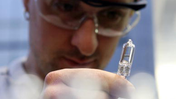 A Philips worker studies a small halogen light on the production line