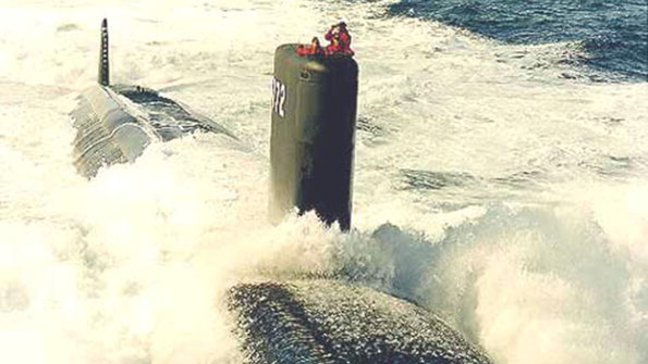 Crew members man the sail as the USS Greenville surfaces