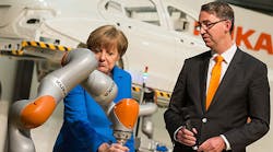 German Chancellor Angela Merkel tests a Kuka robotic arm next to Kuka CEO and chairman Till Reuter.