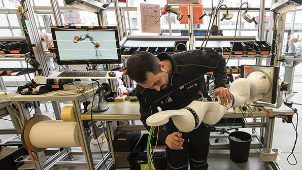 A worker builds a Kuka robotic arm at the companys factory in Augsburg Germany