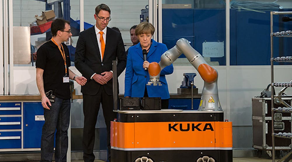 Kuka Robotics CEO Till Reuter, center, and a Kuka employee show off on the company&rsquo;s industrial robots during a visit from German Chancellor Angela Merkel.