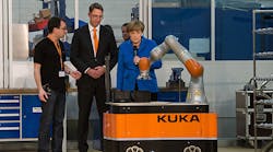 Kuka Robotics CEO Till Reuter, center, and a Kuka employee show off on the company&rsquo;s industrial robots during a visit from German Chancellor Angela Merkel.