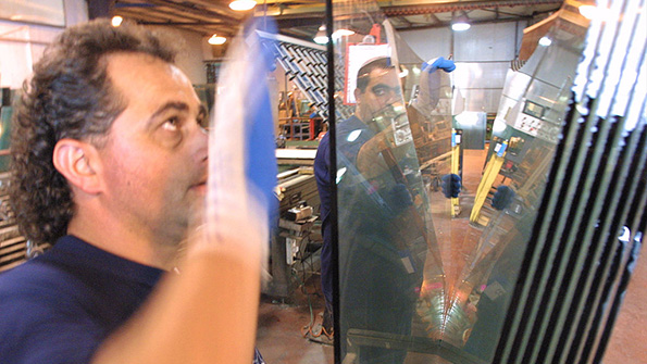 Workers examine sheets at a bulletproof glass factory