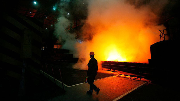 A worker walks past a furnace at a Shanghai Baosteel Group factory