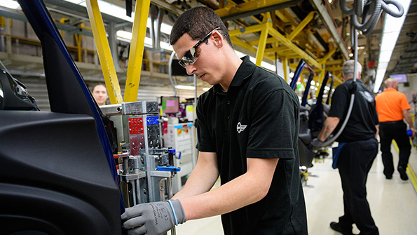 An assembly line employee at work on a Mini in Cowley England