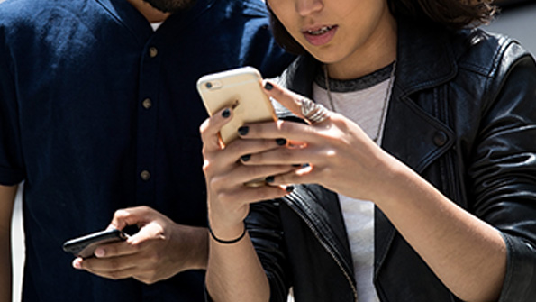A man and a woman play Pokemon Go on their Apple iPhones