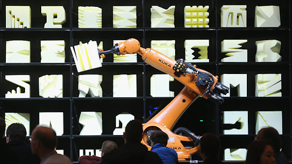 Visitors watch a Kuka robot perform precise movements as part of the Robochop interactive robot installation at the 2015 CeBIT technology trade fair in Hanover Germany