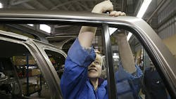 An autoworker installs door panels in a factory An autoworker installs door panels in a factory