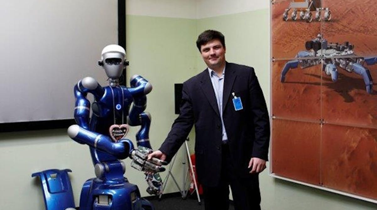 Vladimir Mulukha, of St. Petersburg Polytechnic University, shakes hands with the mobile humanoid &ldquo;Justin,&rdquo; one type of robot utilized in Ford&rsquo;s space robots research project to advance connected vehicle communications.
