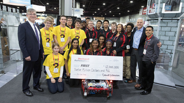Blake Moret left and Jay Flores right of Rockwell Automation presented a ceremonial check for 12M to FIRST President Donald Bossi second from right and two FIRST Robotics teams at Automation Fair