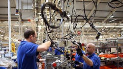 Ford plant employees work on an engine production line Ford plant employees work on an engine production line
