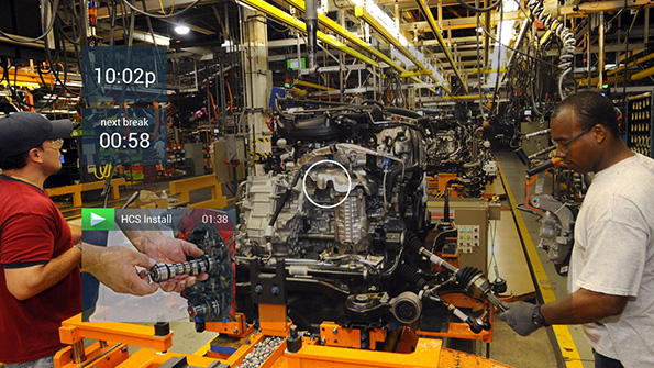Workers assemble equipment while referencing a headsup display HUD