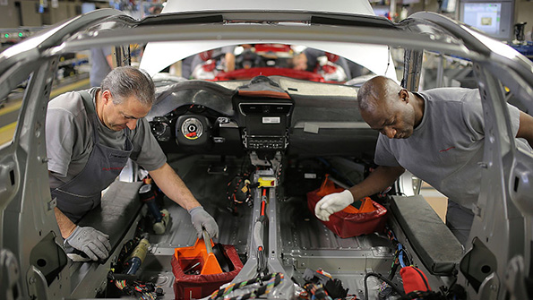 Workers dive into a Porsche which was not among the 16 automakers accused