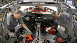 Workers dive into a Porsche which was not among the 16 automakers accused Workers dive into a Porsche which was not among the 16 automakers accused