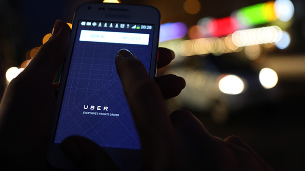 An Uber user opens the app on a smartphone