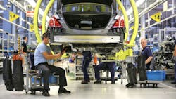Two industrial workers assemble a car at a German factory Two industrial workers assemble a car at a German factory