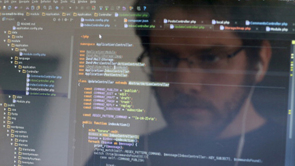 A computer user looks at a screen filled with code