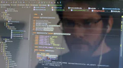 A computer user looks at a screen filled with code