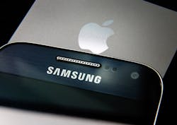 A Samsung and an Apple smartphone, stacked in a pile. A Samsung and an Apple smartphone, stacked in a pile.