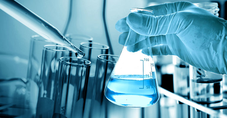 blue gloved hand holding flask with eyedropper