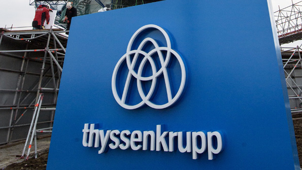 The ThyssenKrupp logo and wordmark in front of a German elevator testing tower