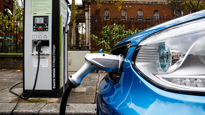 An electric car filling up at the pump.