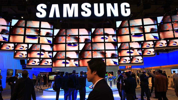 A wall of screens beneath a Samsung logo at a trade show.