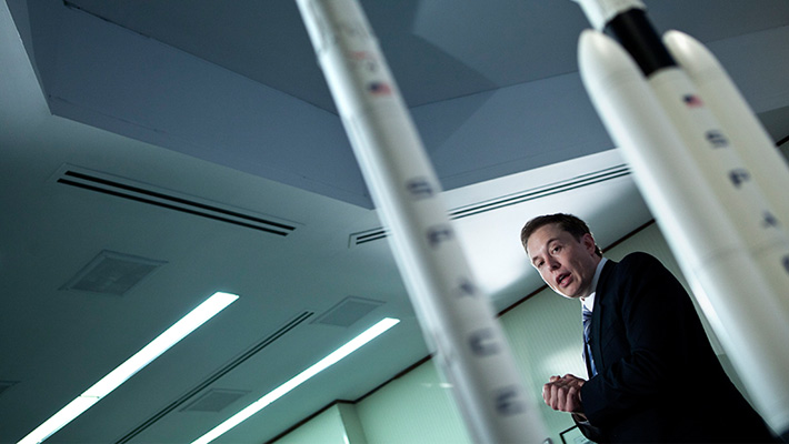 SpaceX CEO Elon Musk in front model rockets.
