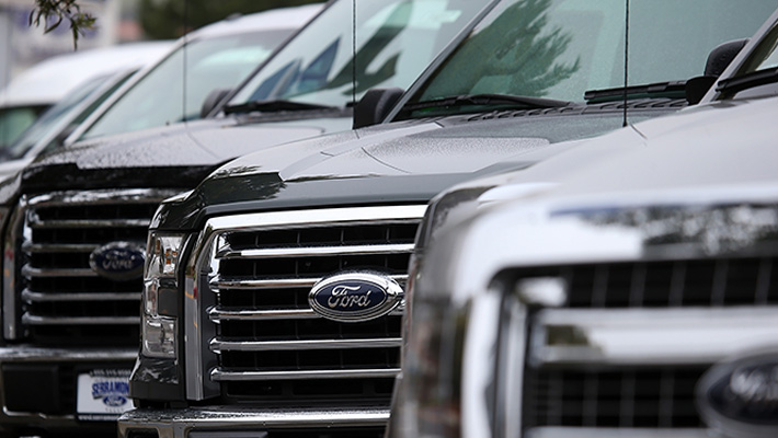 A row of Ford F-Series pickups on a lot.