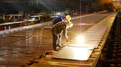 Workers examine hot steel at a mill.