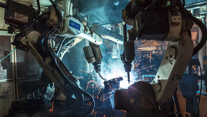 A pair of industrial robots at work on the floor.