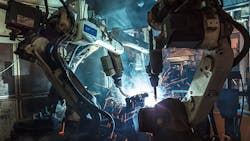 A pair of industrial robots at work on the floor. A pair of industrial robots at work on the floor.