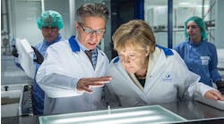 German chancellor Angela Merkel, right, visits a production facility for sterile glass vials at the Sanofi pharmaceuticals plants in Frankfurt.